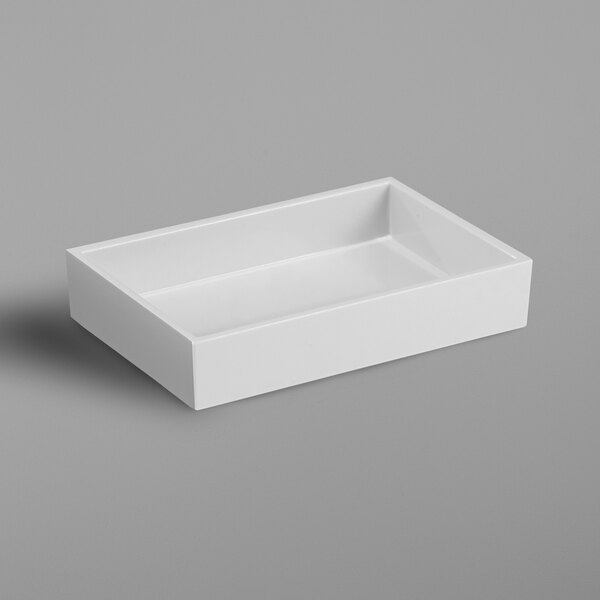 A white rectangular soap dish on a gray surface.