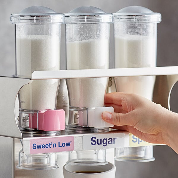 A hand using a Server InSweeten coffee sweetener dispenser to pour white powder.