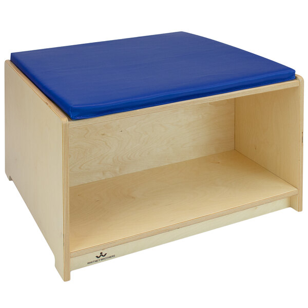 A Whitney Brothers wooden bench with a blue cushion.