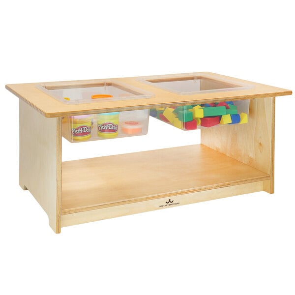 A wooden Whitney Brothers toddler sensory table with plastic bins and toys inside.