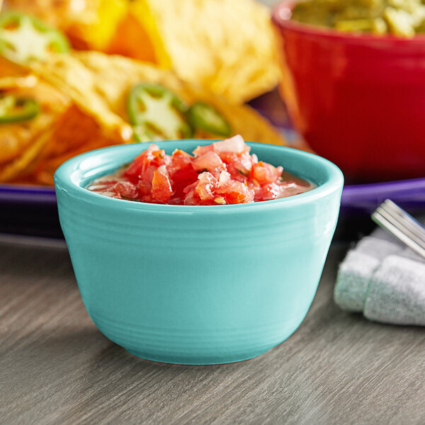 A blue bowl of salsa on a table.