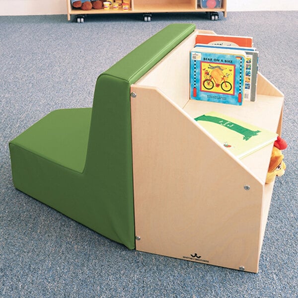 A Whitney Brothers reading nook with a green and beige seat and a book on a shelf.