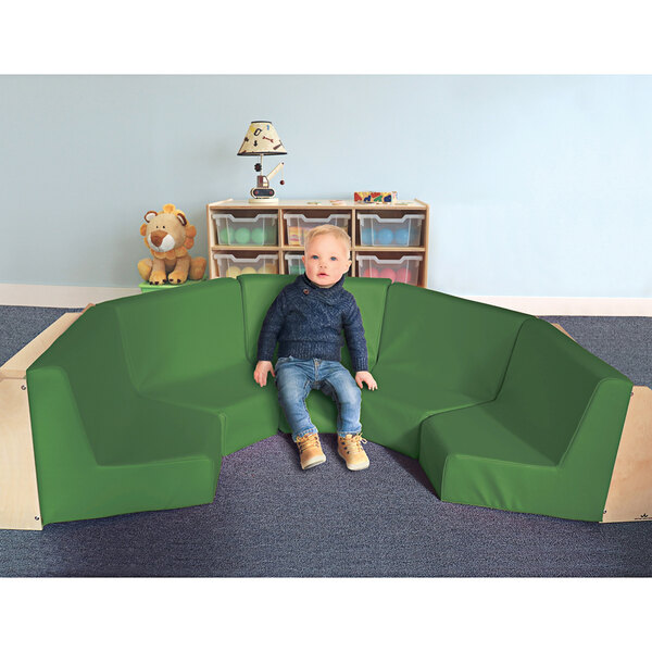 A child sitting in a Whitney Brothers reading nook on a green couch.