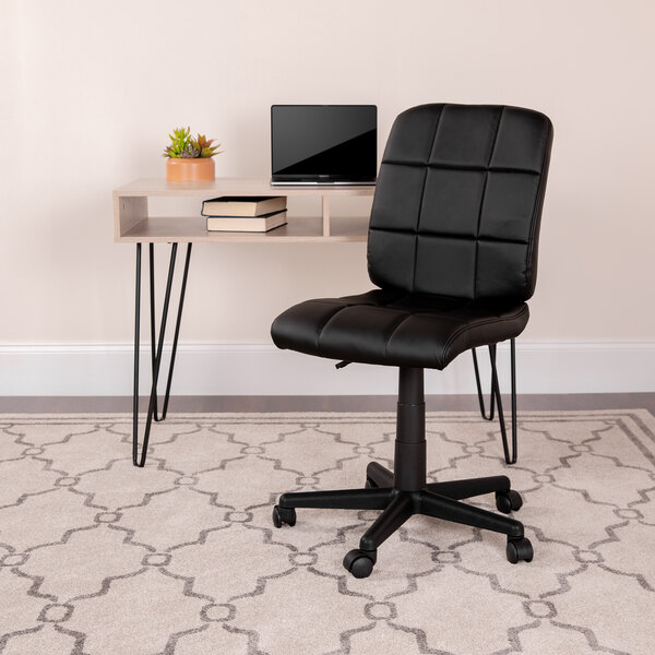 A Flash Furniture black quilted vinyl office chair with wheels next to a desk.