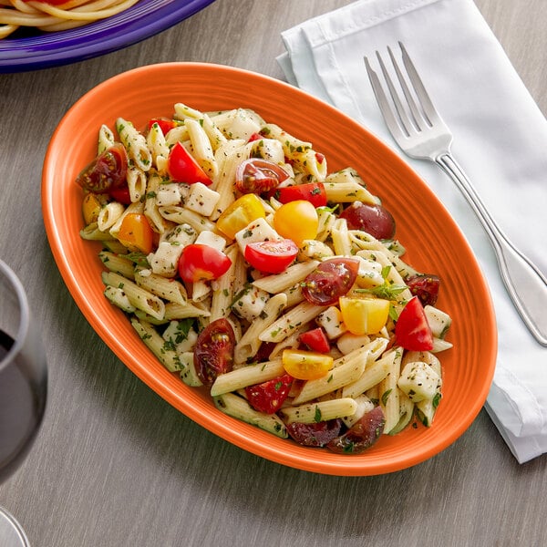 A Tuxton oval china coupe platter with pasta, tomatoes, and cheese on it.