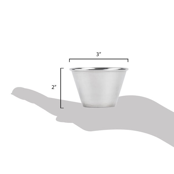 A hand holding a silver American Metalcraft stainless steel sauce cup.