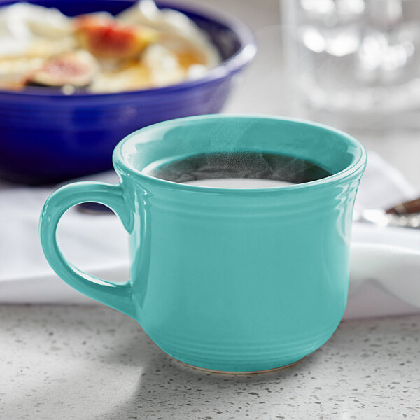 A teal Tuxton Concentrix China cup on a table with food.