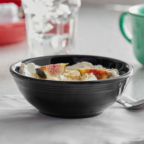 A Tuxton Concentrix black nappie bowl filled with yogurt and fruit on a table.