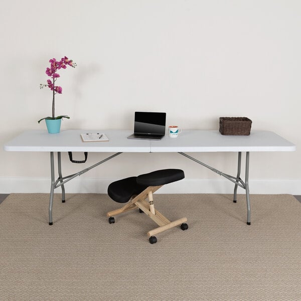 A white Flash Furniture rectangular bi-fold plastic folding table with a laptop on it.