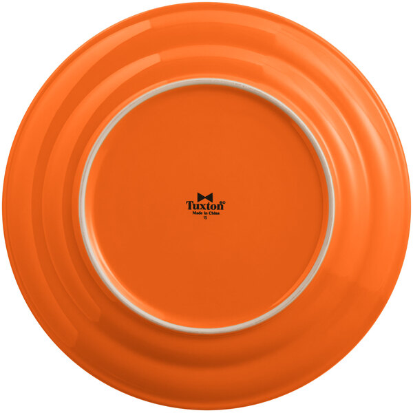 A Tuxton Concentrix papaya orange china plate with a white rim.
