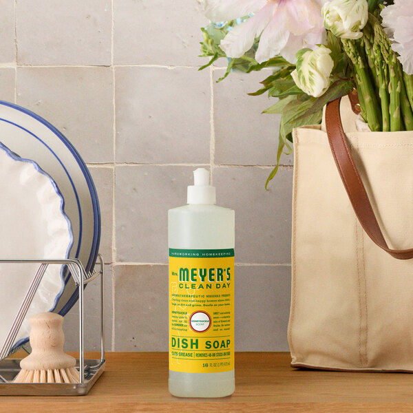A bottle of Mrs. Meyer's Clean Day honeysuckle scented dish soap placed on a kitchen counter.