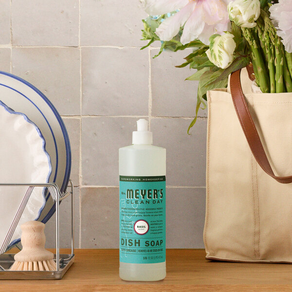 A bottle of Mrs. Meyer's Clean Day 16 oz. basil scented dish soap placed on a kitchen counter.