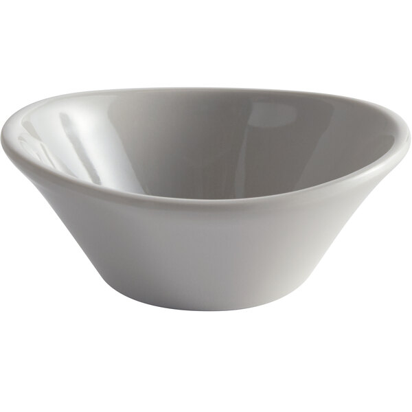 A white Carlisle melamine sauce cup with a spoon inside.