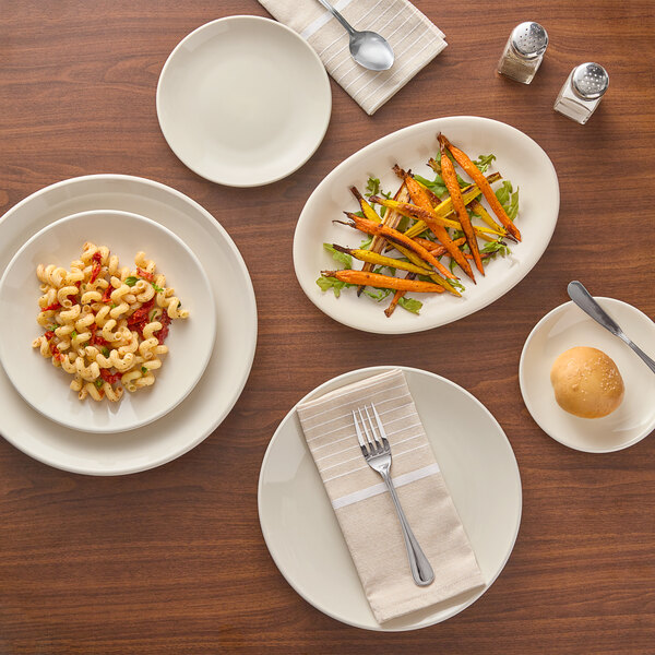 An Acopa ivory stoneware plate with food on a wooden table.