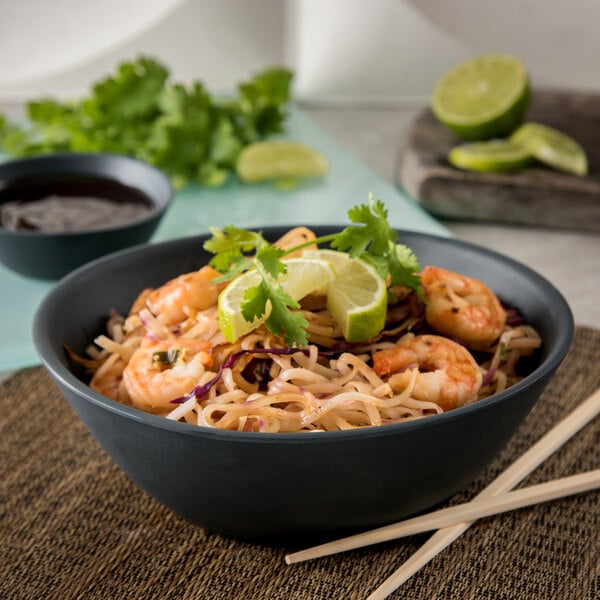 A Carlisle slate melamine bowl of noodles with shrimp and lime slices.