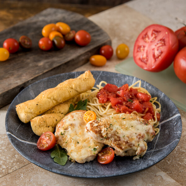 A Carlisle Ridge soapstone melamine dinner plate with chicken and tomato pasta and breadsticks.
