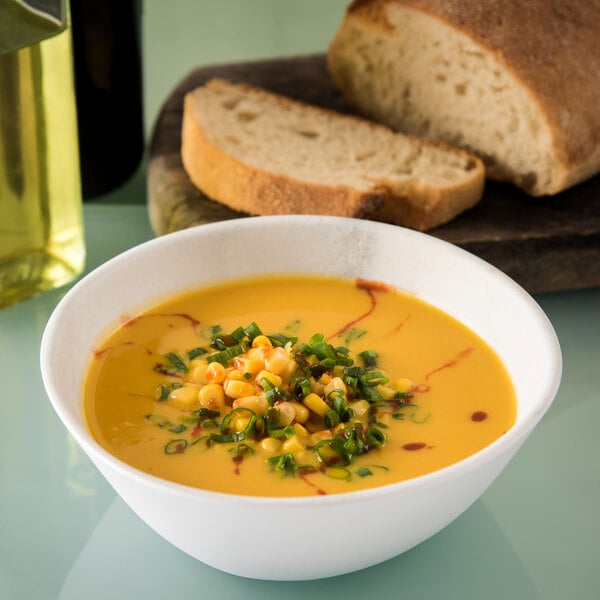 A Carlisle marble melamine bowl filled with soup with corn and chives on a table.