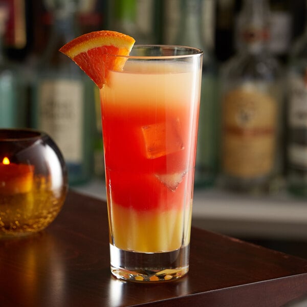 A Libbey Gallery beverage glass with a drink and a slice of orange on a table.