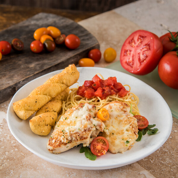 A Carlisle marble melamine dinner plate with chicken, pasta, tomatoes, and breadsticks on a table.