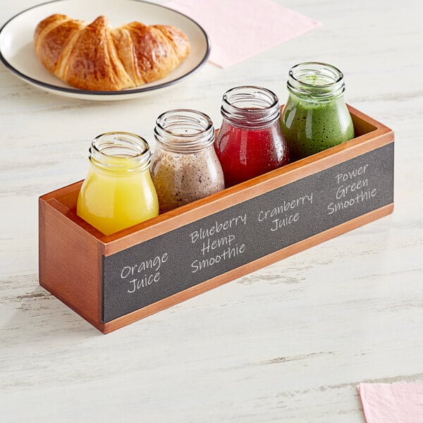 An Acopa wooden flight crate with glass bottles of different juices inside.