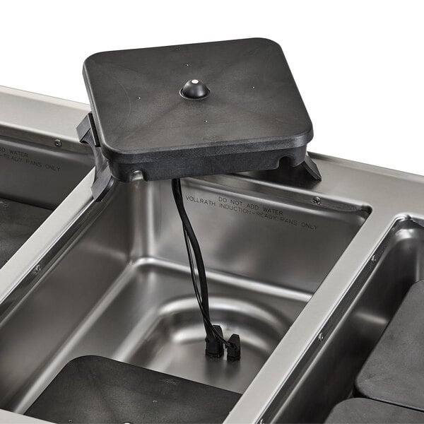 A close-up of a black Vollrath drop-in hot food well surface.
