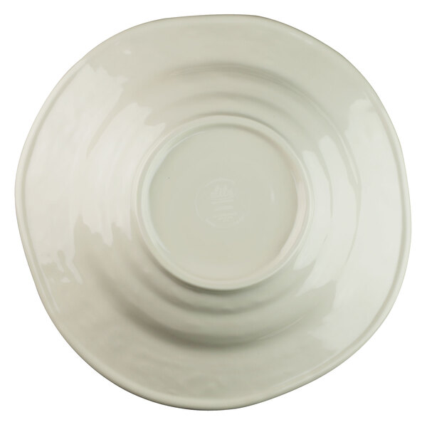 A white melamine bowl with a round beach design in the center on a white plate.