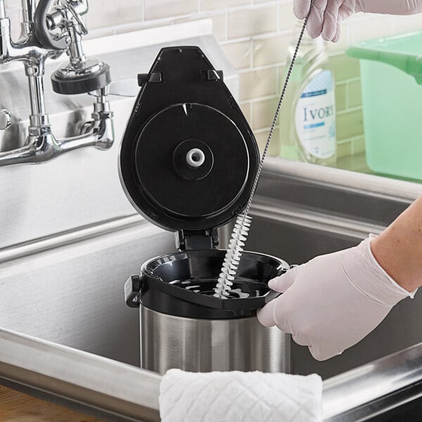 A person using a Carlisle Sparta coffee urn brush to clean a sink in a professional kitchen.