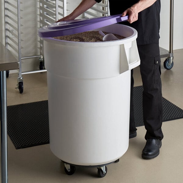 A person holding a purple lid over a large white container.