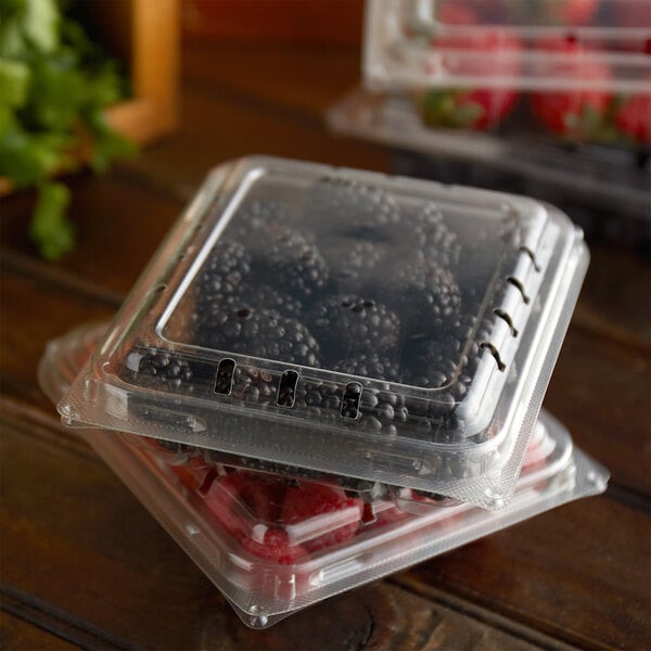 Two stacked plastic clamshell containers holding raspberries and blackberries