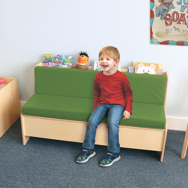 A child sitting on a green bench in a lounge area.
