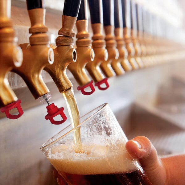 A person using a Chef Master beer tap to pour beer into a glass.