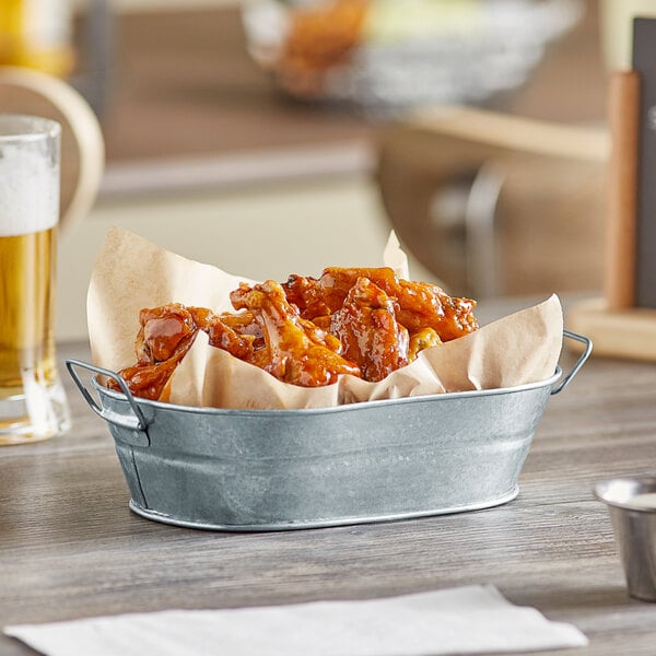 An American Metalcraft galvanized metal oval tub filled with food on a table.