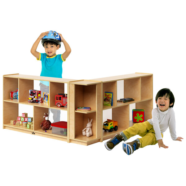 Two children playing with a Whitney Brothers toddler-height storage corner cabinet filled with toys.