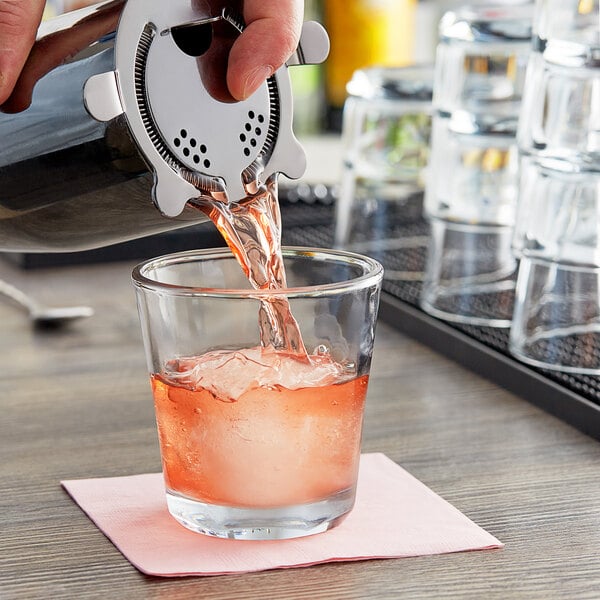 A person pouring a drink into an Anchor Hocking Clarisse cocktail glass.