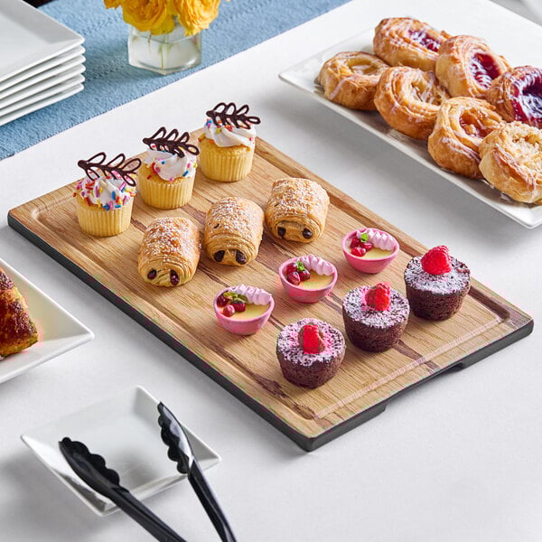 A rectangular melamine display board with pastries and desserts on a table.