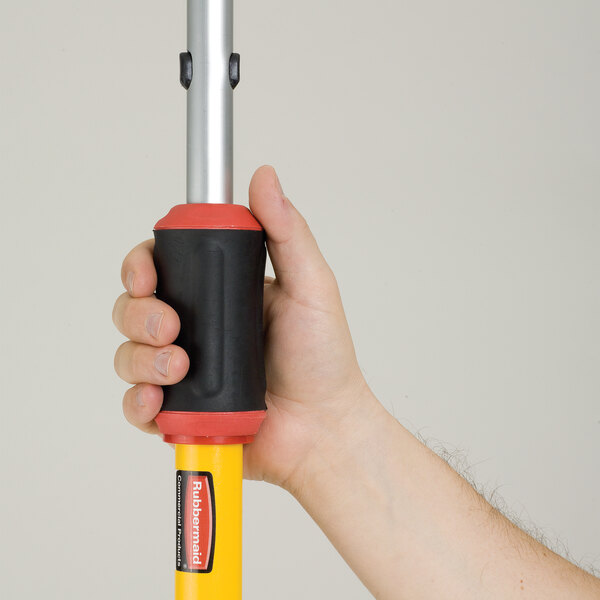 A person using a yellow and black Rubbermaid Quick-Connect telescopic pole.