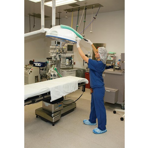 A green microfiber dusting sleeve replacement attached to a cleaning tool being used in a hospital operating room.