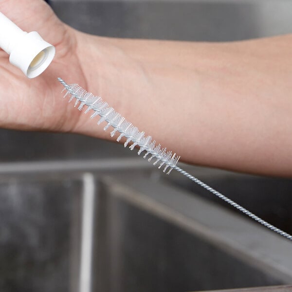 A person using a Carlisle Sparta condiment dispenser spout brush.