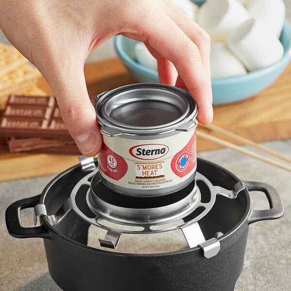 A hand holding a can of Sterno S'mores Heat fuel.