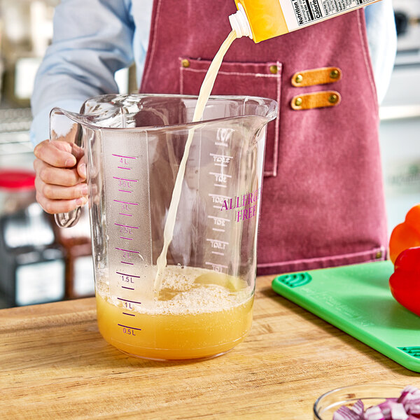 A person pouring milk into a purple Choice plastic measuring cup.