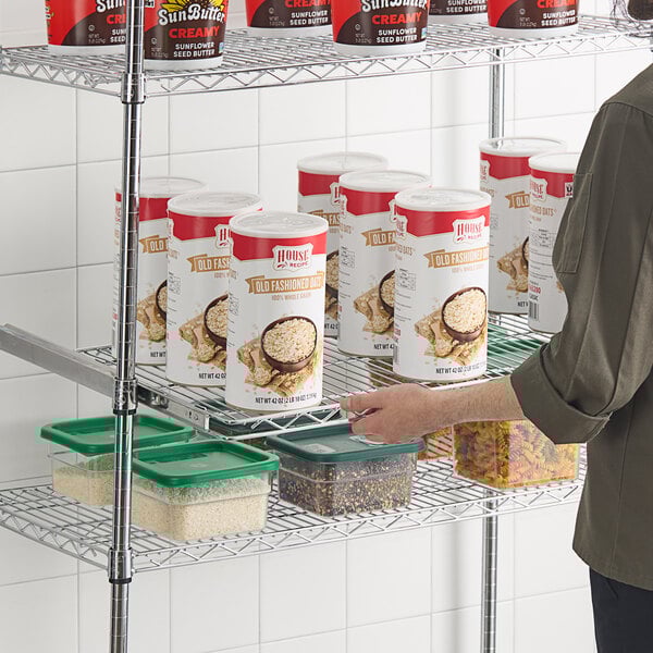 A woman sliding a white container of food onto a Regency chrome wire shelf.