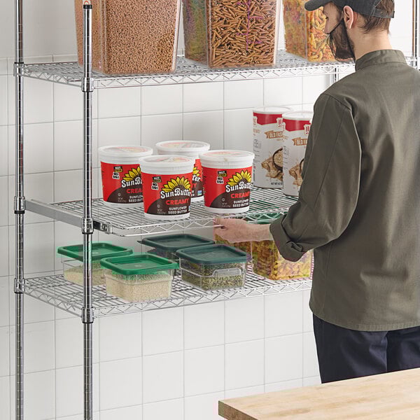 A man standing in front of a Regency chrome wire shelf with food containers.