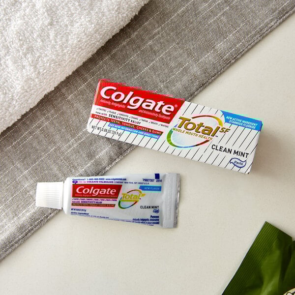 A Colgate Total Clean Mint toothpaste tube next to a towel.
