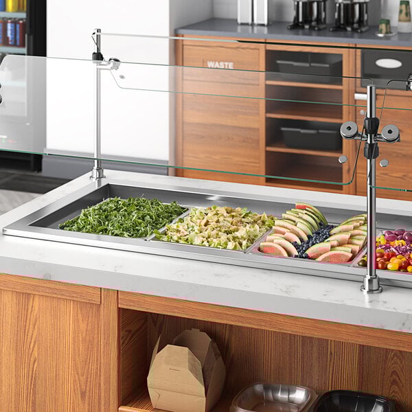 A Delfield drop-in refrigerated cold food well holding four pans on a counter in a salad bar.