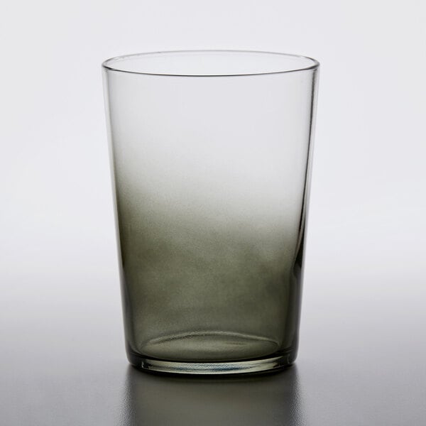 An Arcoroc grey beverage glass with a dark liquid in it.