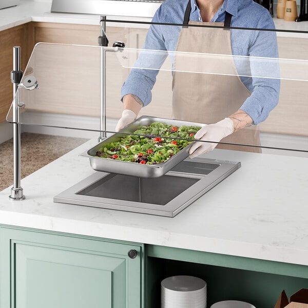 A man using a Delfield drop-in cold food well to prepare a tray of food for a salad bar.