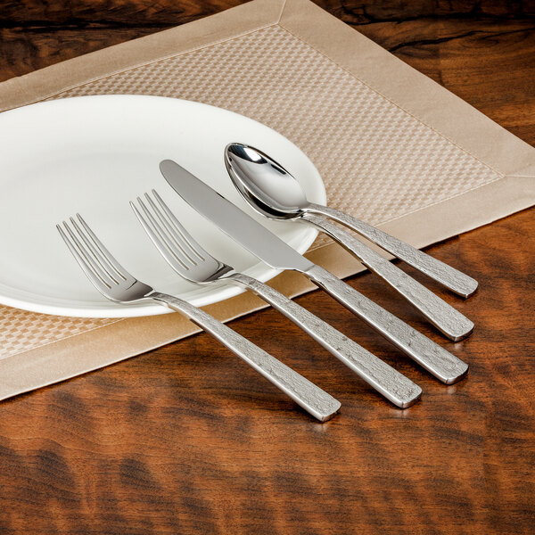 A white plate with a Walco Vestige stainless steel dinner knife and fork on it.