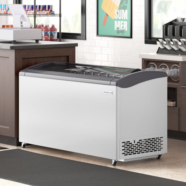 A Beverage-Air glass top display freezer on a counter in a store.