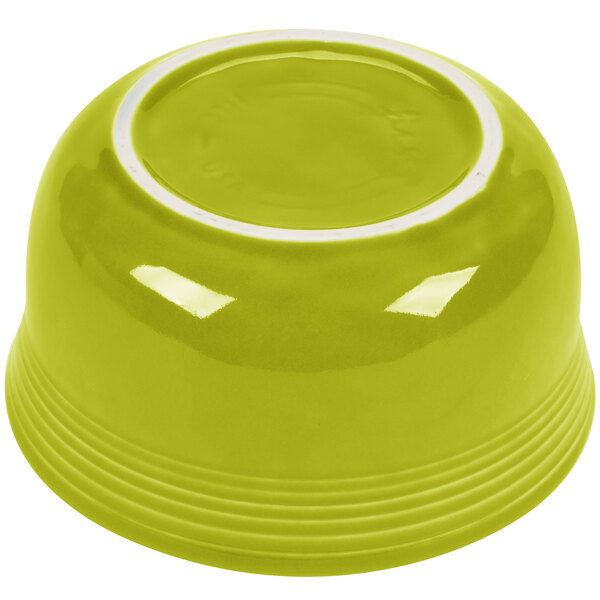 A close up of a Fiesta Lemongrass China Gusto Bowl with a white rim on a green surface.