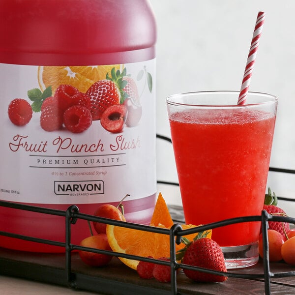 A bottle of Narvon fruit punch syrup next to a glass of red liquid.